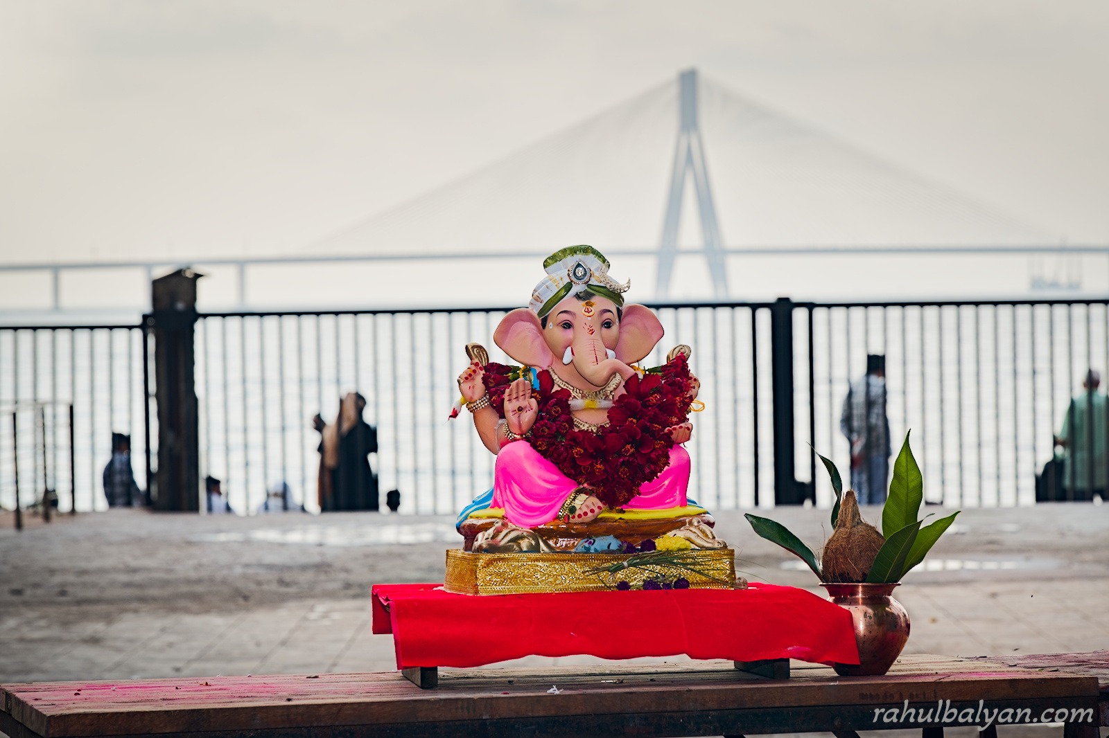 Ganesha idol on a red cloth beside a copper kalash, the Bandra-Worli Sea Link hazy in the background